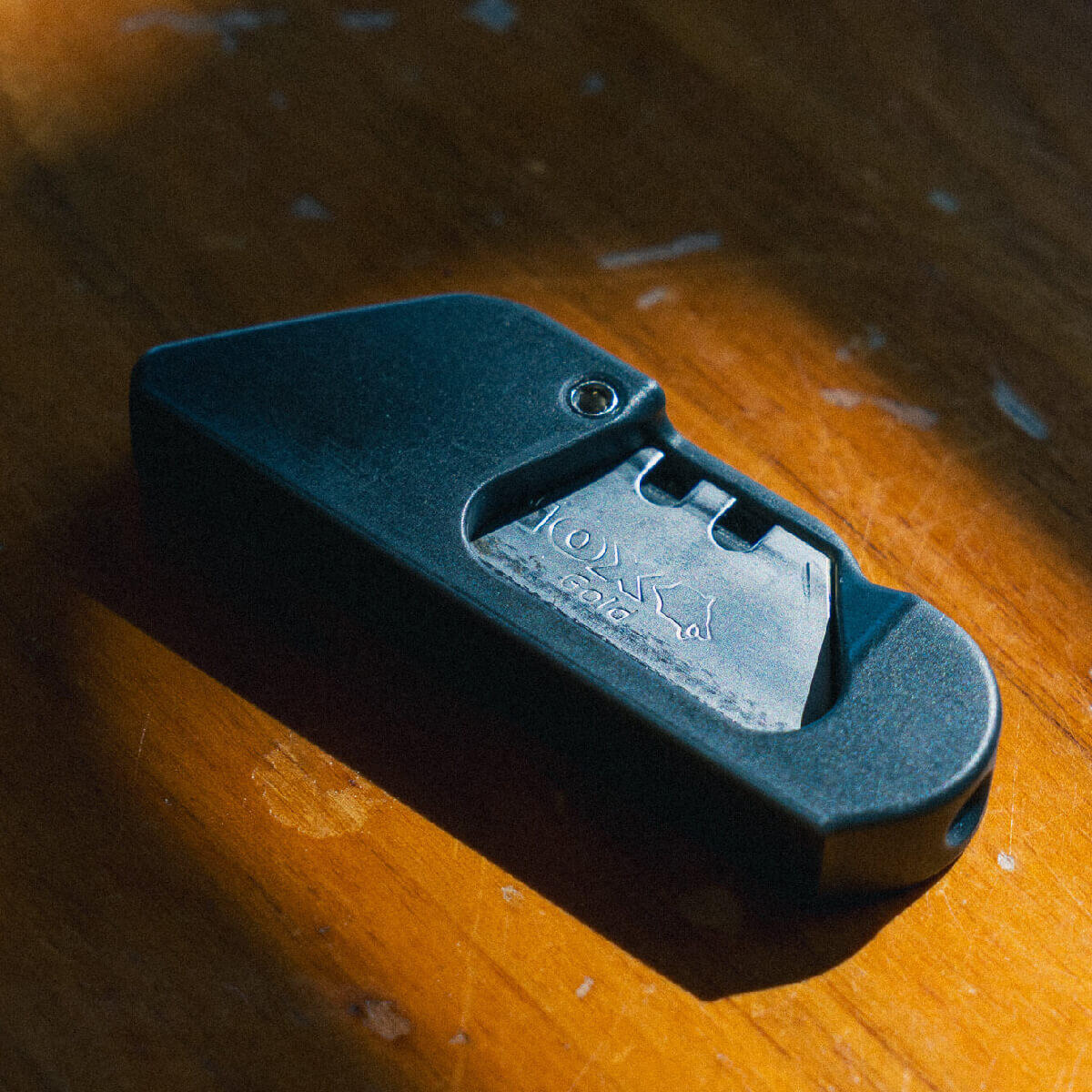 Clicky Cutter – Compact EDC Box Cutter with Retractable Blade Clicky Cutter compact EDC box cutter with blade extended, angled top view on warm wood surface